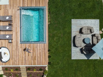 Hotel Schmung: wellness at Alpe di Siusi/Seiser Alm Aerial view of pool with wooden deck and seating area on green lawn