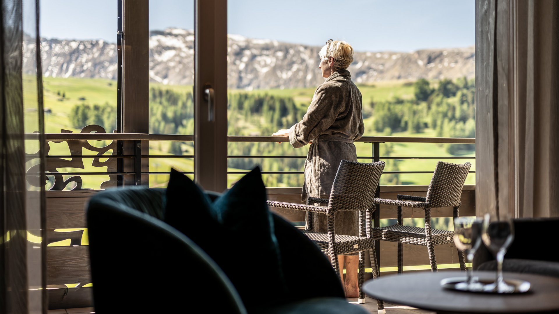 Hotel Schmung – Ihr Hotel auf der Seiser Alm Frau in Bademantel auf Balkon mit Bergblick bei klarem Wetter