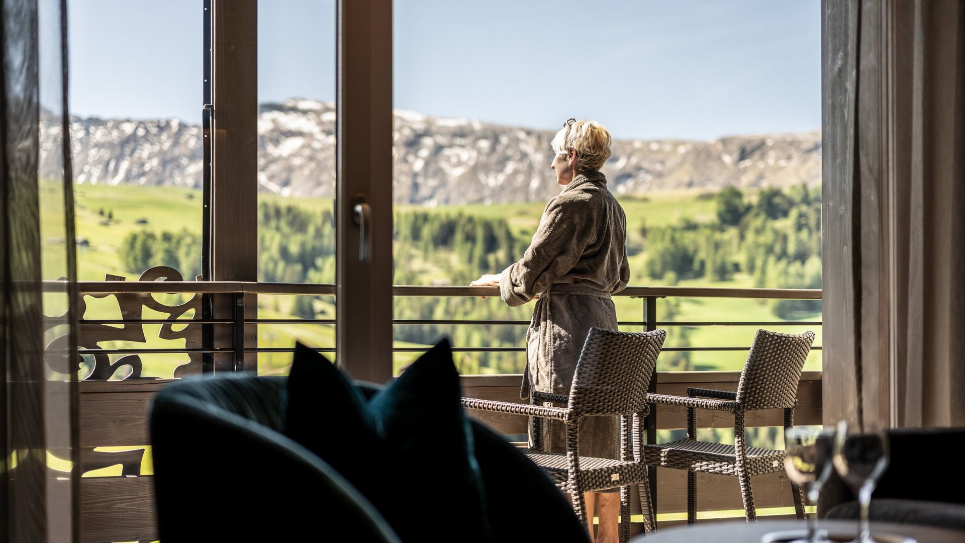 Ihre Unterkunft auf der Seiser Alm Frau in Bademantel auf Balkon mit Bergblick bei klarem Wetter