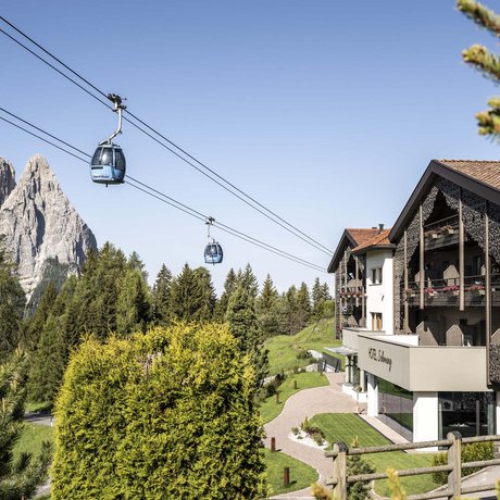 Hotel Schmung: our picture gallery Cable car cabins above green trees with mountain and hotel in the background
