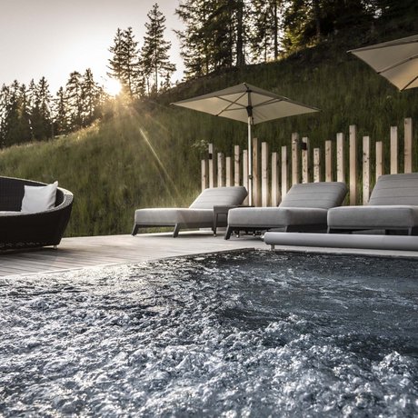 Hotel Schmung: our picture gallery Hot tub with lounge chairs and umbrellas by wooded hillside at sunset