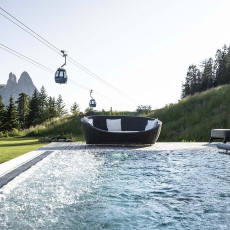 Hotel Schmung: our picture gallery Pool with seating area, loungers, and cable car in front of mountains