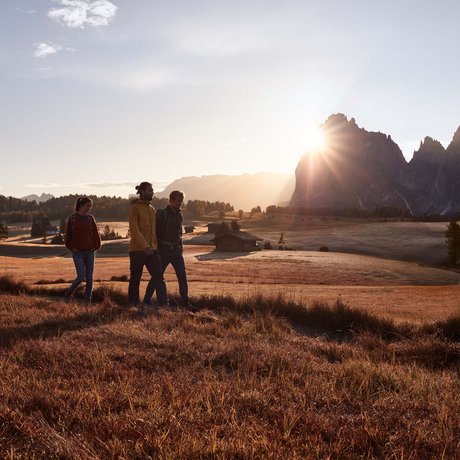 Hotel Schmung: our picture gallery Three hikers at sunset on a mountain meadow with a cabin in the background