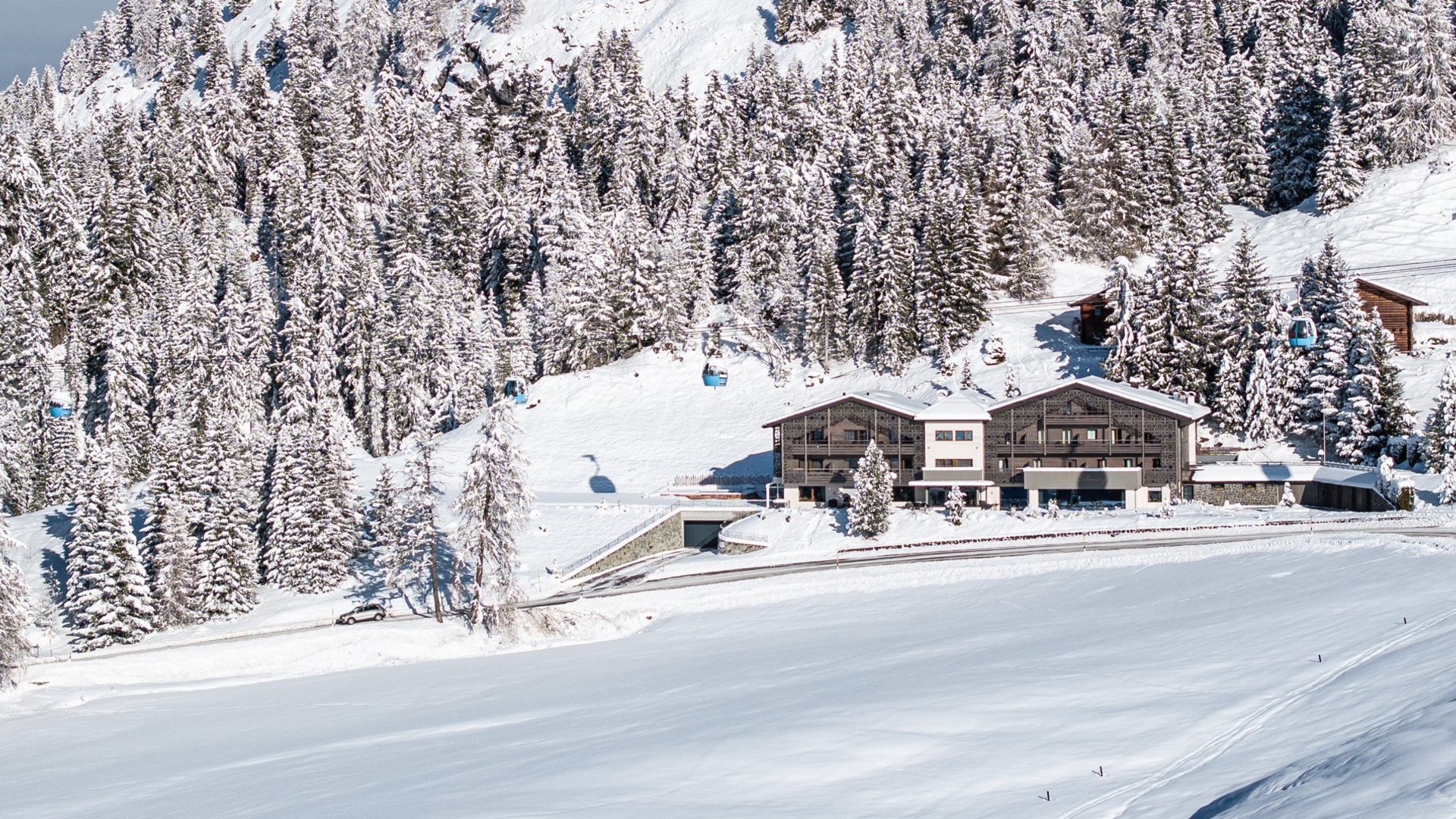 Schneebedecktes Chalet und Wälder an einem sonnigen Winterberg