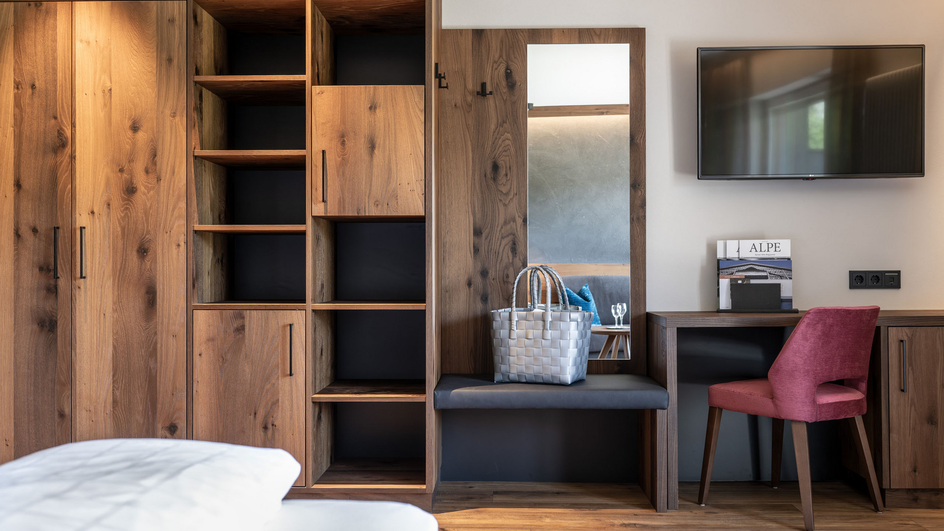 Hotel Schmung – Ihr Hotel auf der Seiser Alm Holzkleiderschrank mit Spiegel und TV im modernen Schlafzimmer