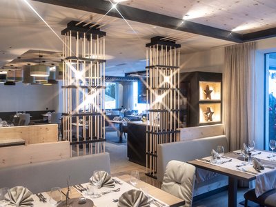 Il nostro hotel con jacuzzi in Alto Adige Ristorante moderno e luminoso con dettagli in legno e tessuto, tavoli elegantemente apparecchiati