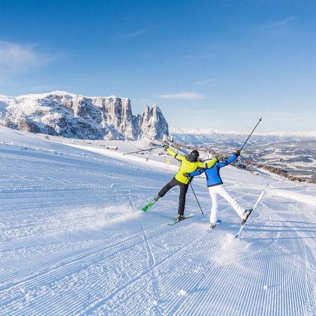 Hotel Schmung: our picture gallery Two skiers on snowy slope with mountain background and clear blue sky