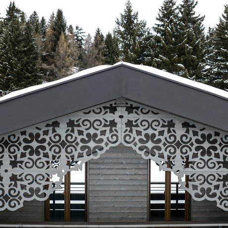 Hotel Schmung: our picture gallery Snow-covered gable roof with decorative wood carvings in front of pine forest