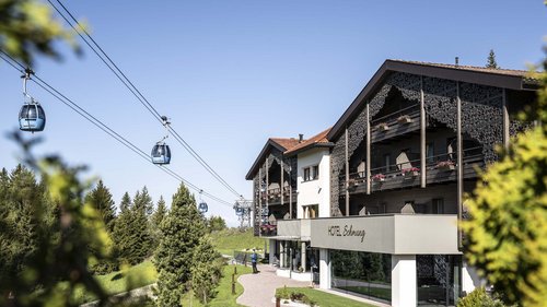 Dolomiti Springdays Hotel Schmung con cabine della funivia in paesaggio montano verde sotto cielo azzurro