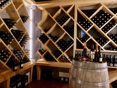Culinary highlights at Hotel Schmung Wine cellar with wooden racks and barrel displaying wine bottles and glasses