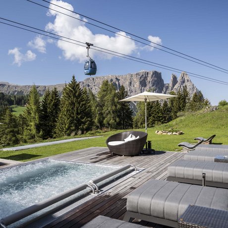Hotel Schmung: our picture gallery Wellness area with pool, loungers, and cable cars against mountain backdrop
