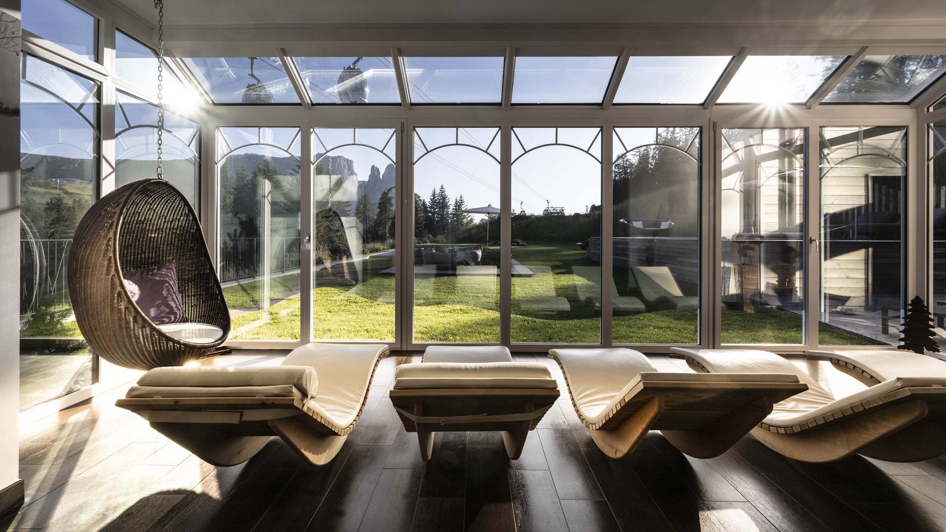Hotel Schmung: wellness at Alpe di Siusi/Seiser Alm Sunny relaxation room with lounge chairs and view of mountains and garden