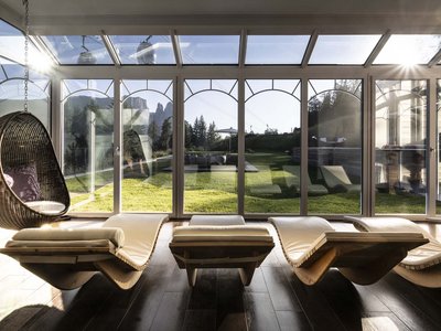 Il nostro hotel con jacuzzi in Alto Adige Sala relax soleggiata con poltrone lounge e vista sulle montagne e giardino