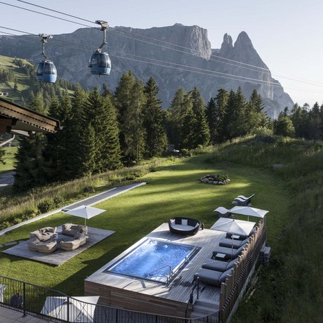 Hotel Schmung: our picture gallery Mountain view with cable cars, pool, seating area, and lawn beside a house