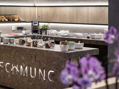 Culinary highlights at Hotel Schmung Modern breakfast buffet with bread, cereals, and bowls in a restaurant