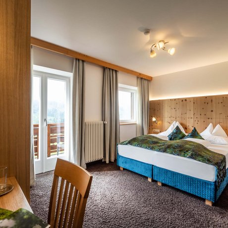 Hotel Schmung: our picture gallery Bright hotel room with double bed, balcony, and wooden paneling