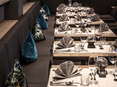 Culinary highlights at Hotel Schmung Elegant set tables with folded napkins and colorful cushions on bench seating