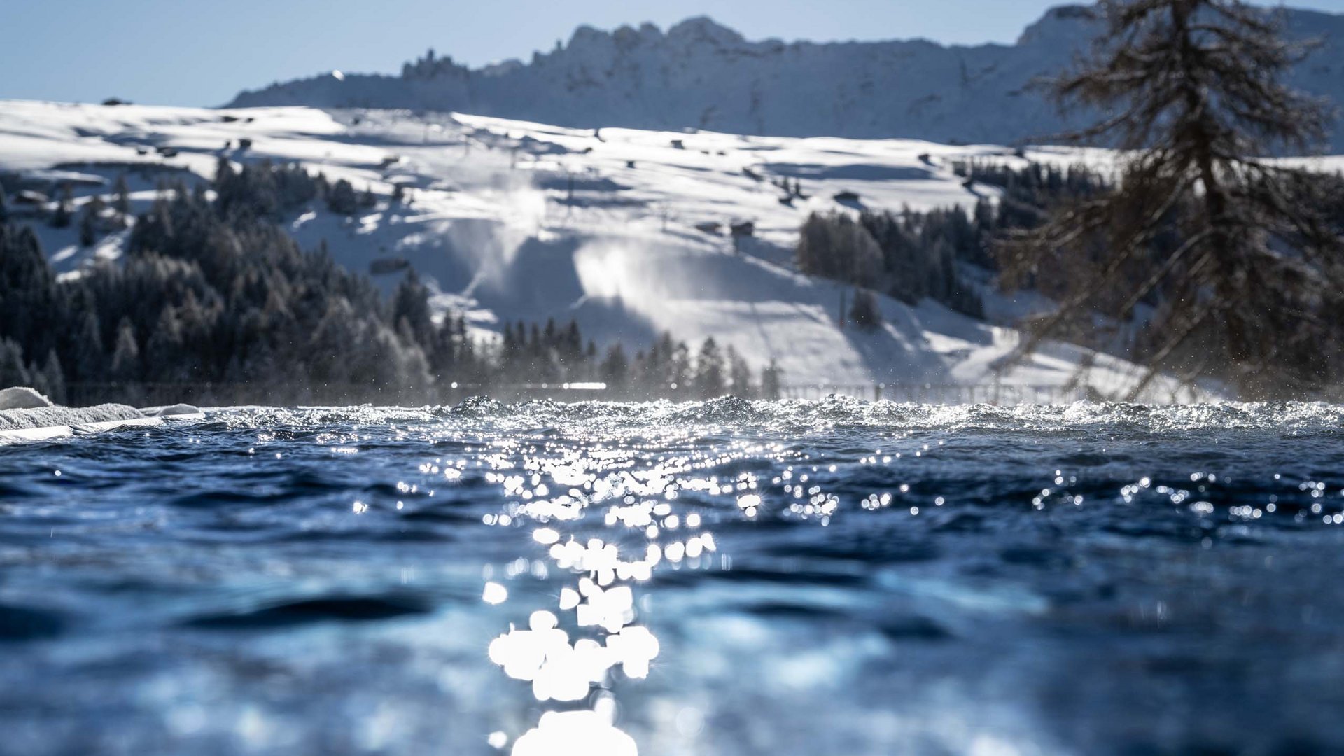 Hotel Schmung: wellness at Alpe di Siusi/Seiser Alm Snowy mountain ski area with shimmering water in the foreground