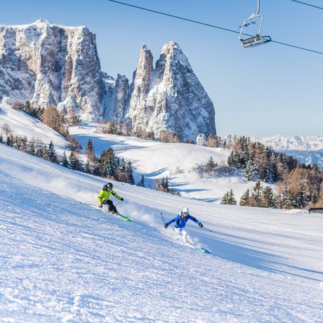 Hotel Schmung: our picture gallery Two skiers skiing on snowy slope under chairlift with mountains in background
