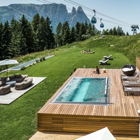 Hotel Schmung: our picture gallery Pool area with loungers and cable car on green meadow in summer mountains