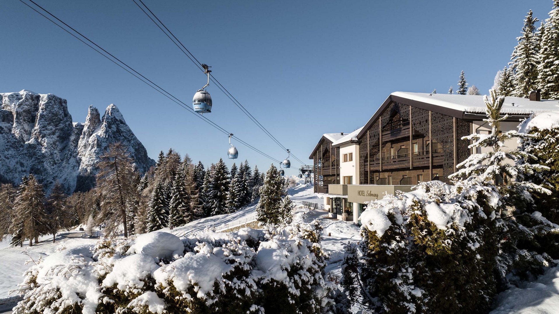 Hotel innevato in montagna con cabinovia e cielo limpido