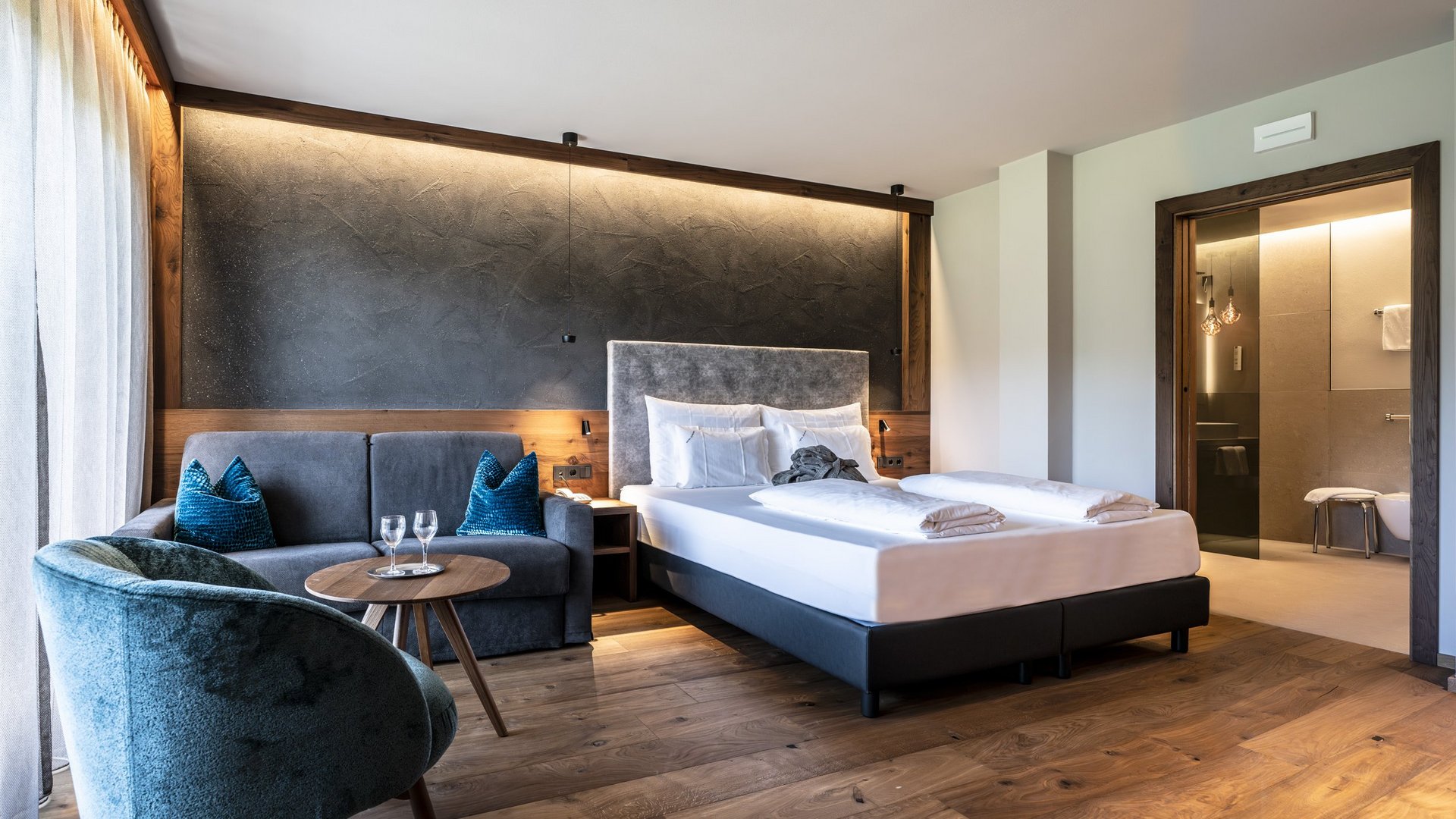 Ihre Unterkunft auf der Seiser Alm Modernes Hotelzimmer mit Doppelbett, Sofa und Badezimmer