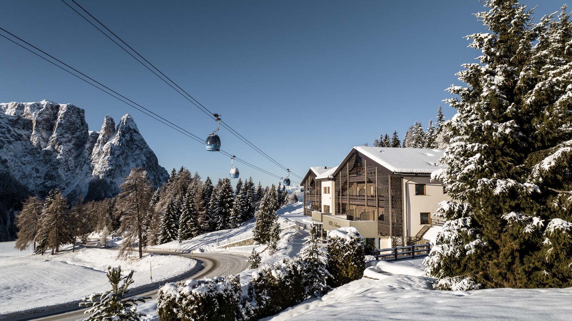 Paesaggio alpino innevato con funivia e hotel sotto un cielo limpido