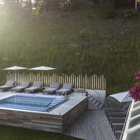 Hotel Schmung: our picture gallery Modern wooden pool with lounge chairs and umbrellas beside green hill