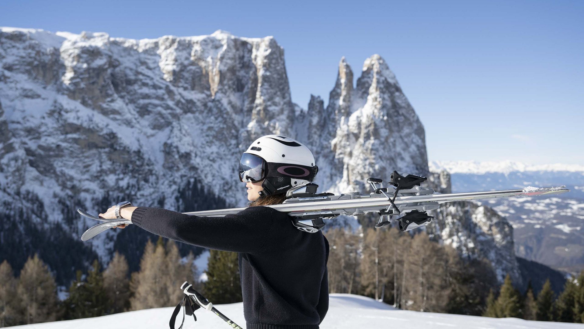 Winterurlaub auf der Seiser Alm imHotel Schmung Frau mit Ski und Helm vor verschneiten Bergen
