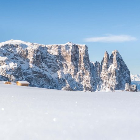 Hotel Schmung: our picture gallery Snow-covered mountains with two wooden cabins under clear blue sky