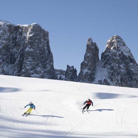 Hotel Schmung: our picture gallery Two skiers on snow with snowy rocks and clear blue sky in background