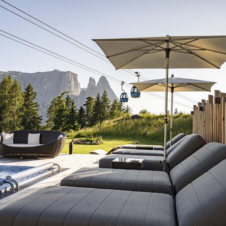 Hotel Schmung: our picture gallery Sun loungers and umbrellas by pool with cable cars and mountains in background