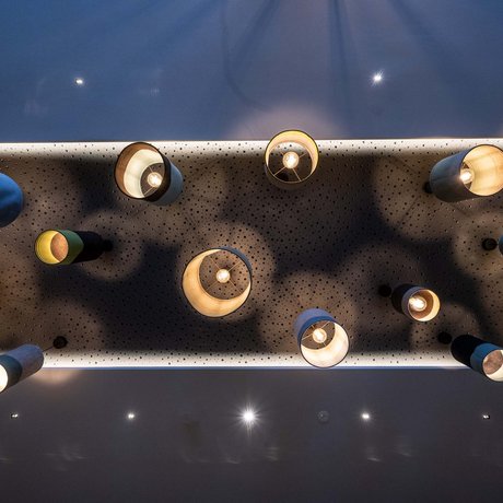 Hotel Schmung: our picture gallery Ceiling lamps of different sizes and colors casting shadows on perforated surface
