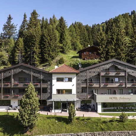 Hotel Schmung: our picture gallery Alpine hotel building with decorative facade and forest background under clear sky