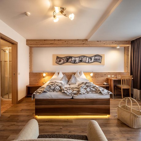 Hotel Schmung: our picture gallery Bright hotel room with double bed, wooden floor, window with curtains and desk