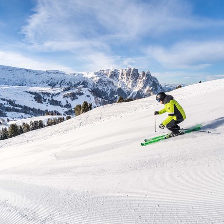 Hotel Schmung: our picture gallery Skier in green jacket skiing on snowy slope with mountains in background