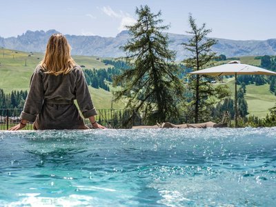 Hotel Schmung: wellness at Alpe di Siusi/Seiser Alm Woman in bathrobe overlooking mountain landscape by the pool