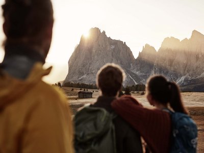 Hotel Schmung: hiking holiday at Alpe di Siusi/Seiser Alm Three people watching the sun setting over the Dolomites
