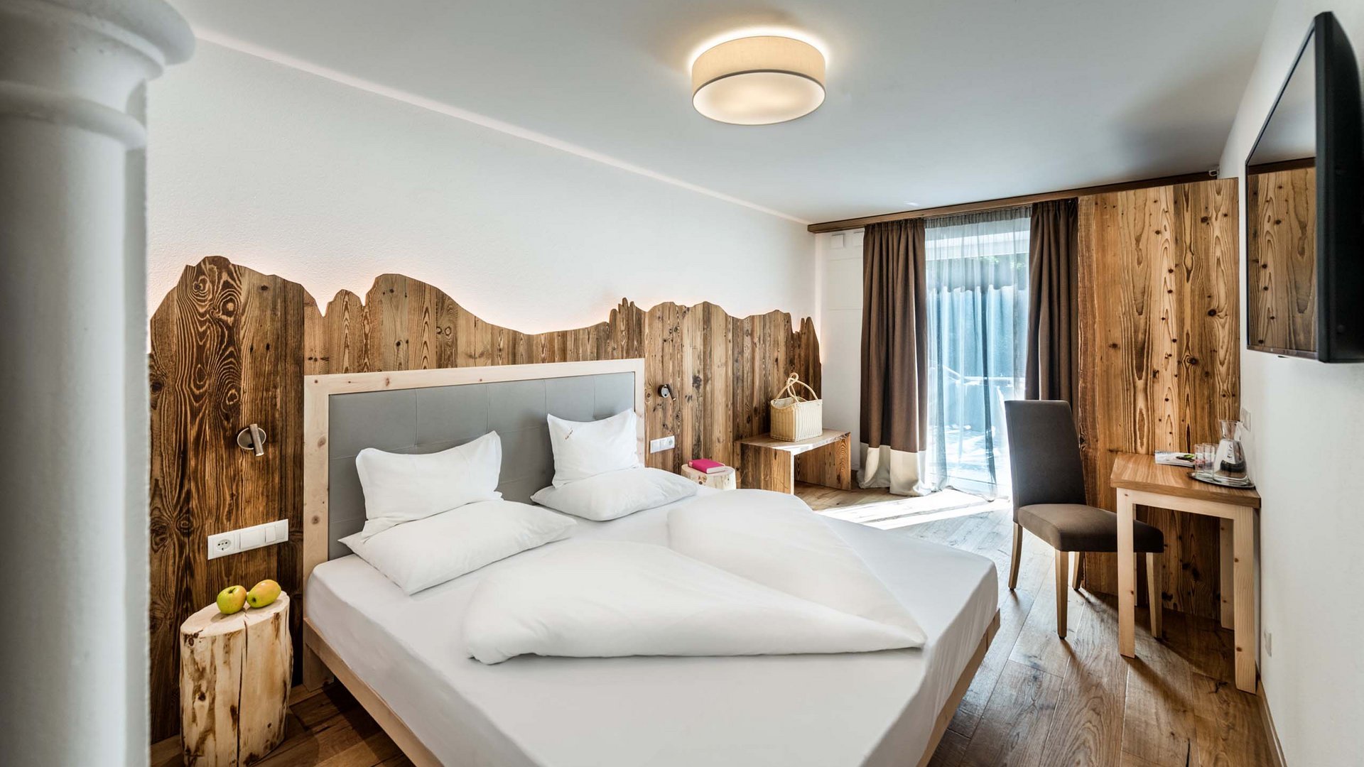 Tutte le info per la vostra vacanza all’Alpe di Siusi Camera d'hotel moderna con elementi in legno e letto grande
