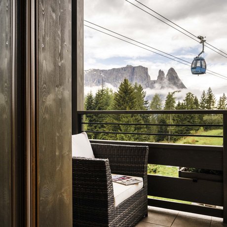 Hotel Schmung: our picture gallery Balcony with wicker chair, mountain view and cable car gondolas in the Alps