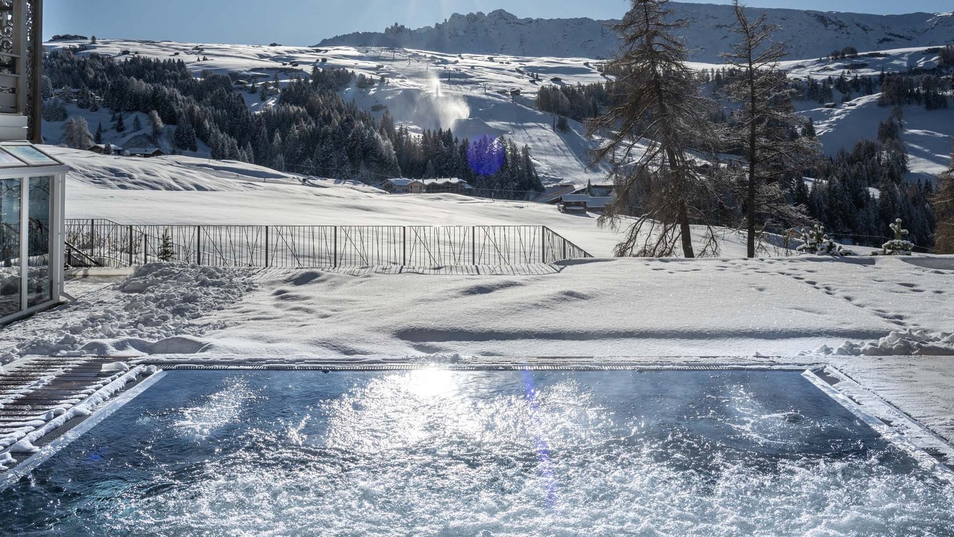 Winterlandschaft mit Schneehügeln, Seilbahnkabinen und Whirlpool unter klarem Himmel