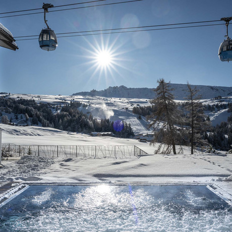 Hotel Schmung: unsere Bildergalerie Winterlandschaft mit Schneehügeln, Seilbahnkabinen und Whirlpool unter klarem Himmel