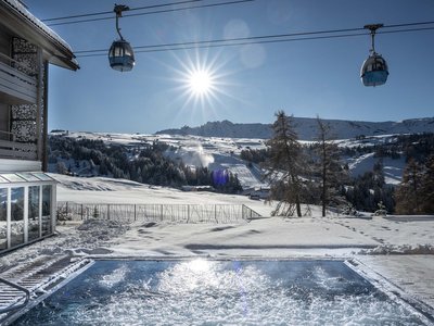 Il nostro hotel con jacuzzi in Alto Adige Paesaggio invernale con pendii innevati, cabine della funivia e piscina riscaldata