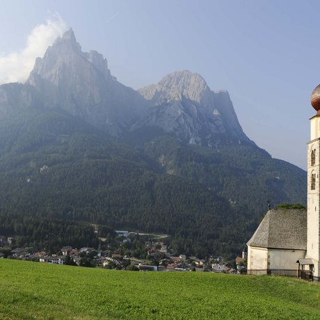 Hotel Schmung: our picture gallery Church tower with forested mountains and village in valley under clear sky