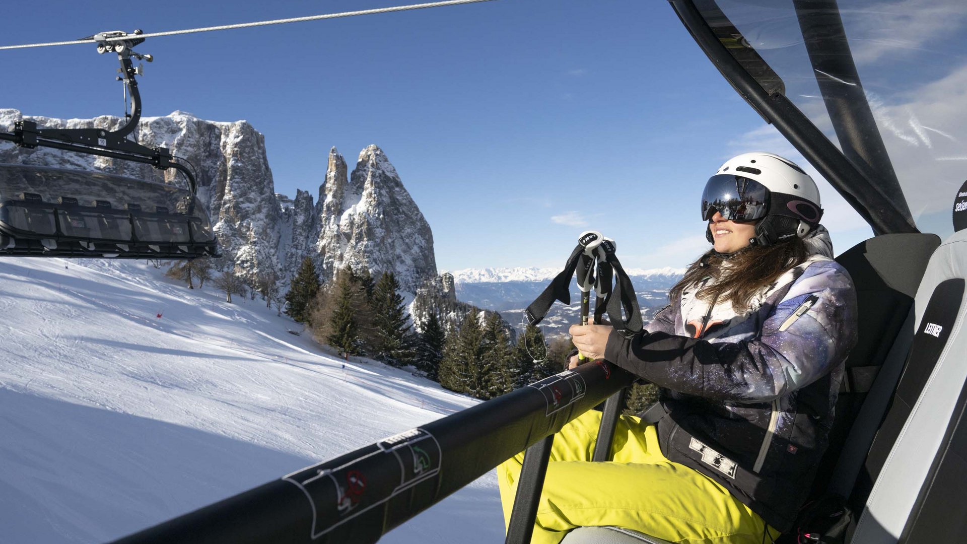 Winterurlaub auf der Seiser Alm imHotel Schmung Frau sitzt in Skilift mit Bergblick im Schnee